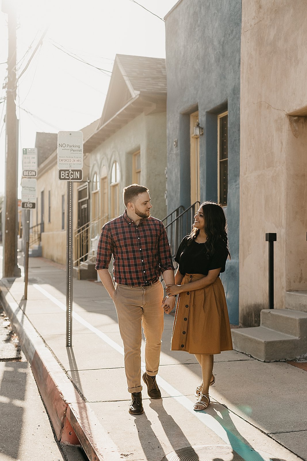 engagement pictures of couple walking in the street by colorful adobe houses in tucson arizona by samantha patri photography