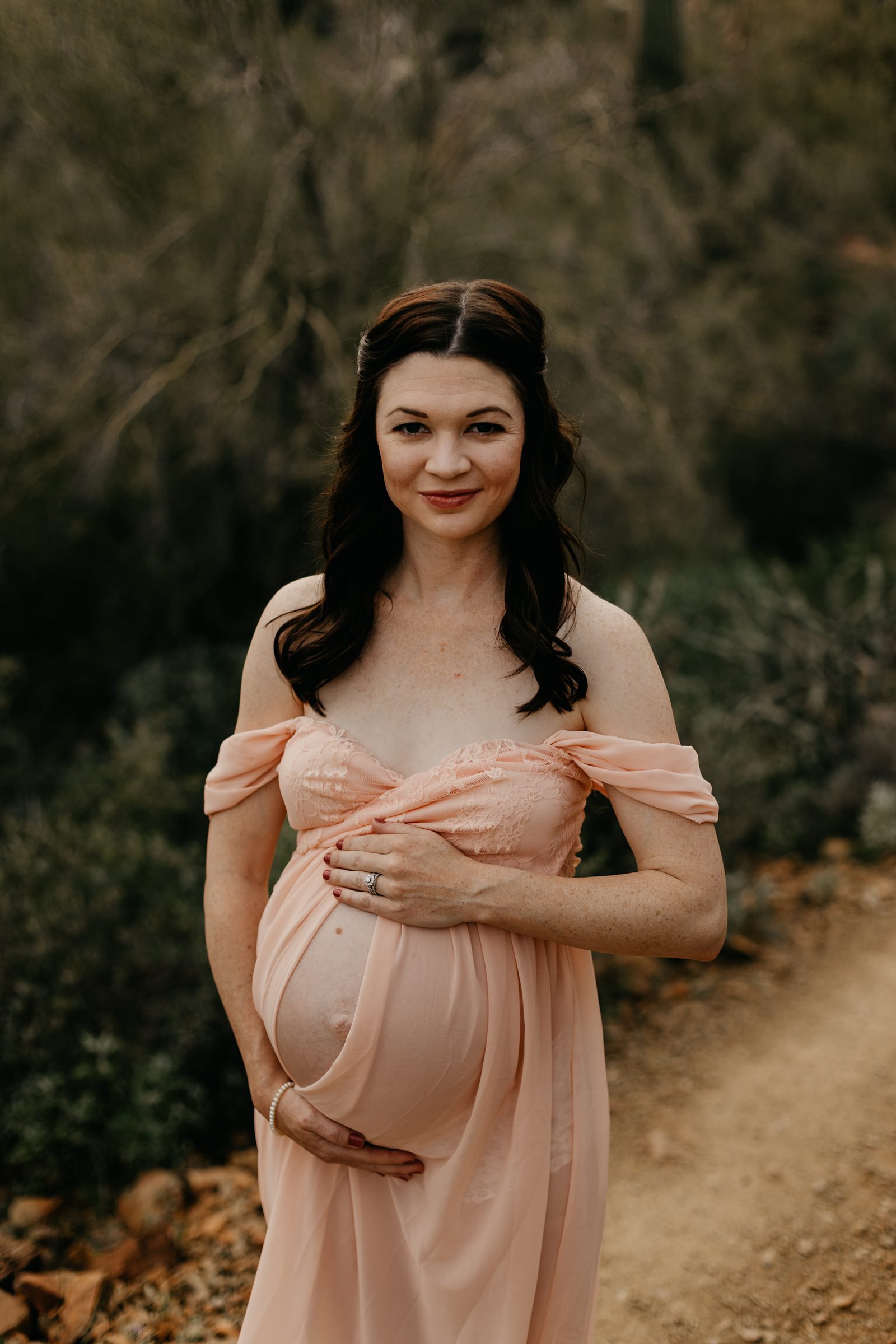 Pregnant woman in pink dress split down for her desert maternity photos in Black Canyon City AZ