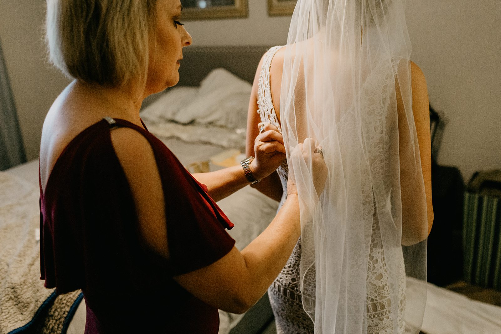 Mom helping the bride get into her wedding dress in Mom's bedroom