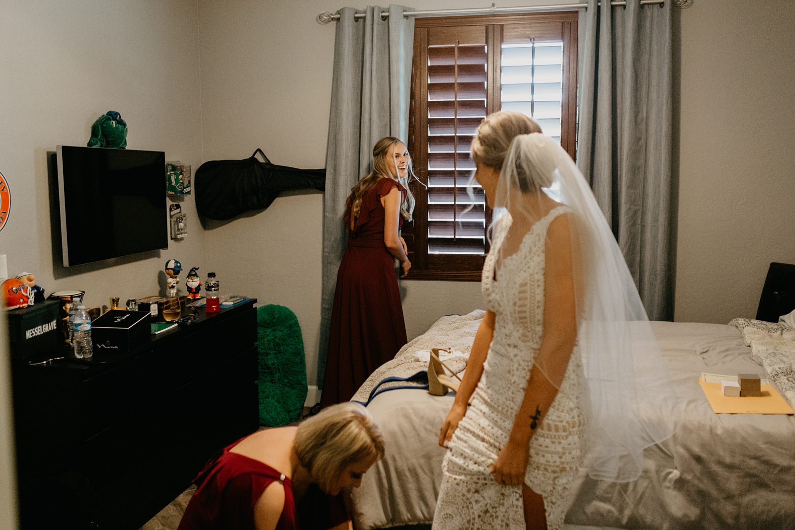 Bride getting ready in her parent's bedroom laughing with her bridesmaid