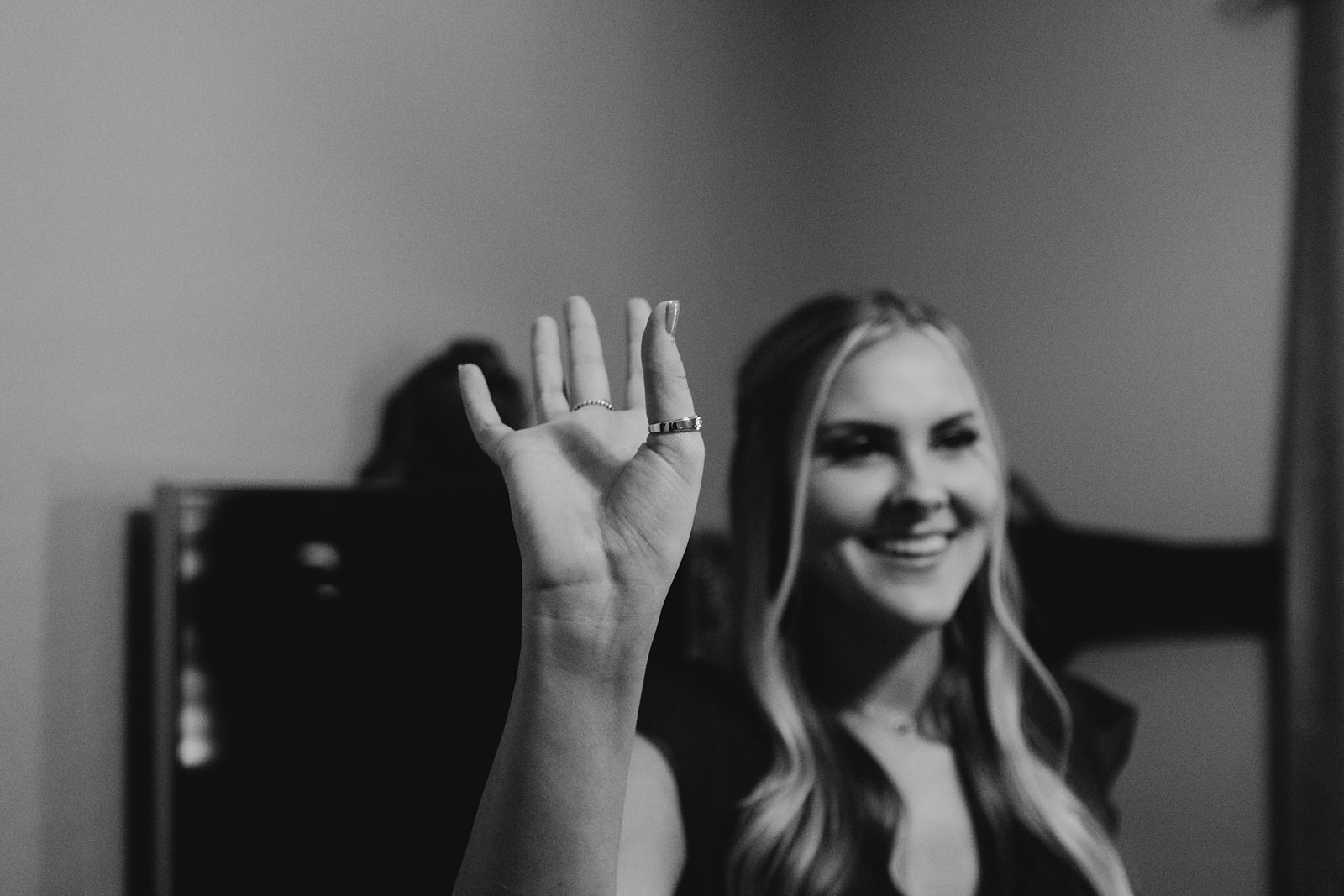 Black and white photo of bridesmaid being silly with the wedding rings