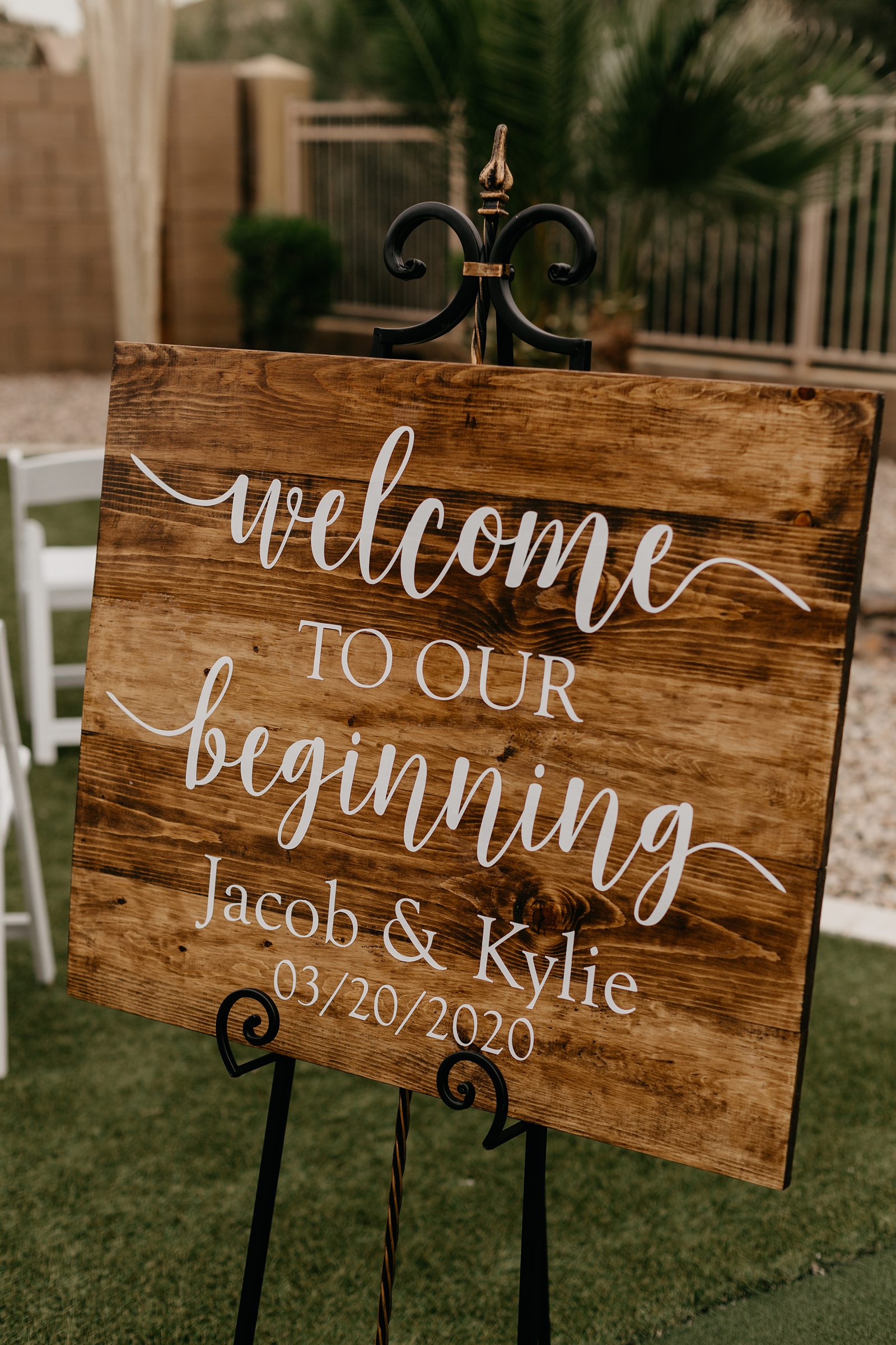 Wooden wedding ceremony sign that says welcome to our beginning with the couple's names and date