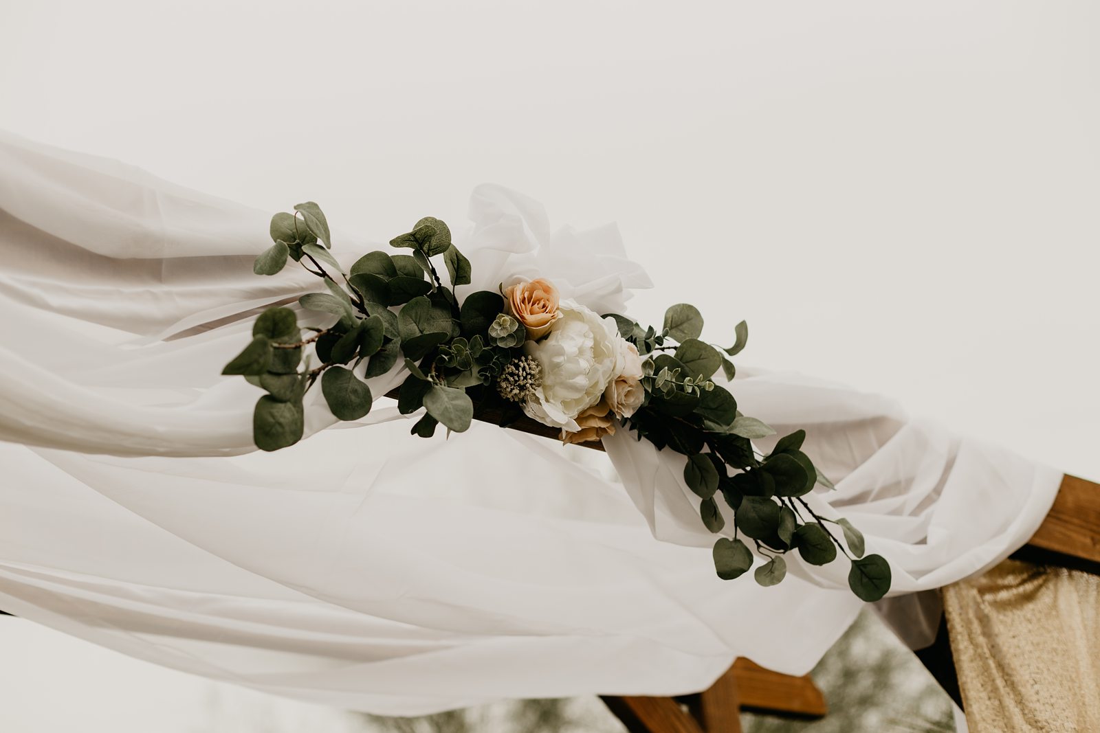 Ceremony arch decorated with cloth flowers and eucalyptus