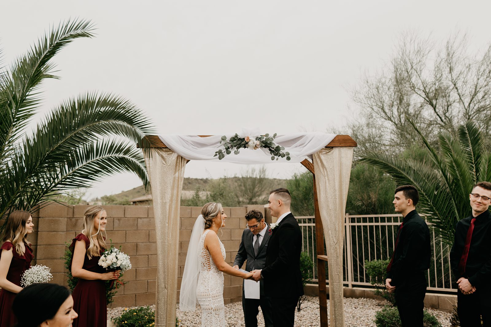 A couple holding hands under the altar during their backyard wedding in Phoenix Arizona on a cloudy day