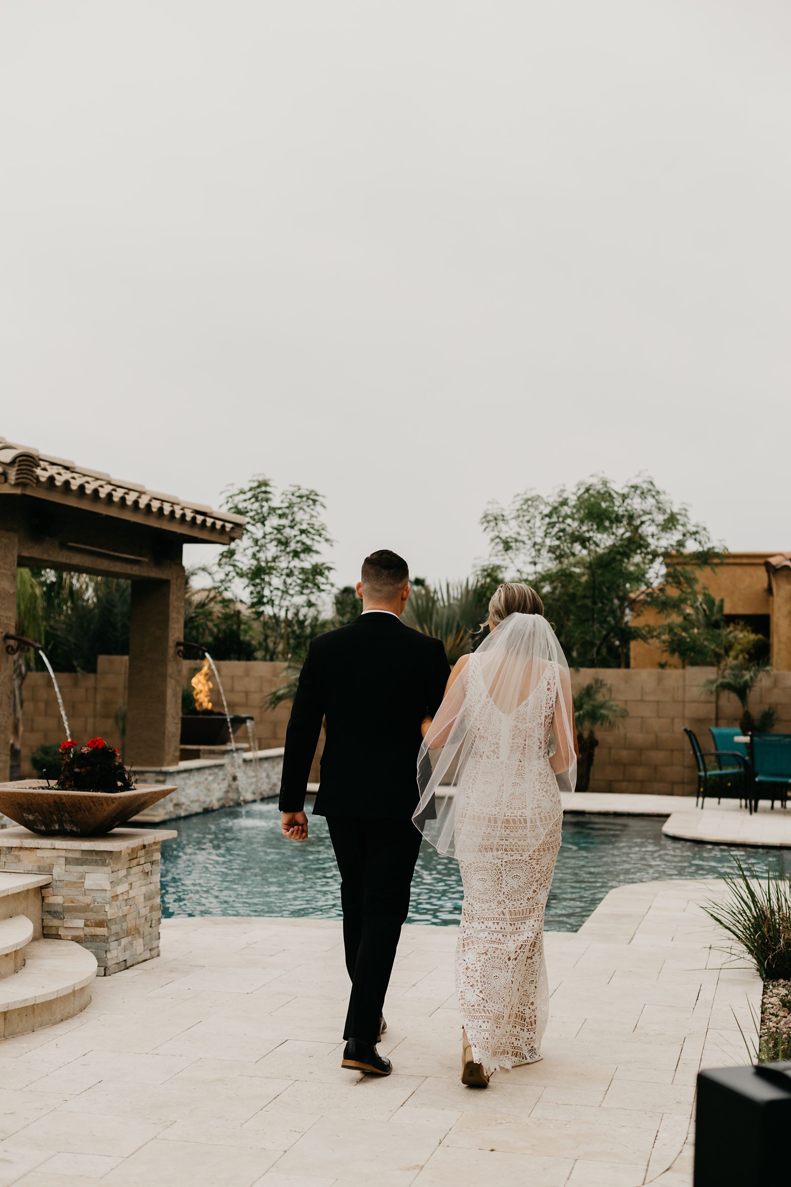 Bright and groom walking by the pool for their intimate wedding photos