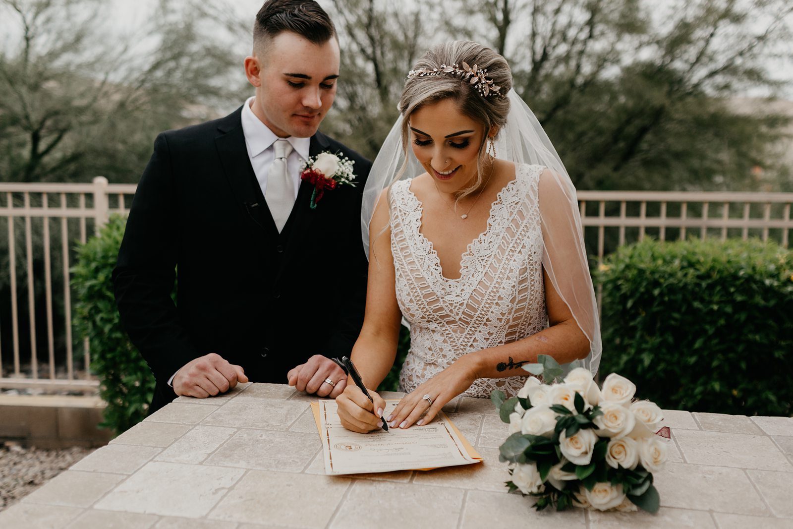 Bright and groom casually signing their marriage license in their intimate backyard wedding in Arizona