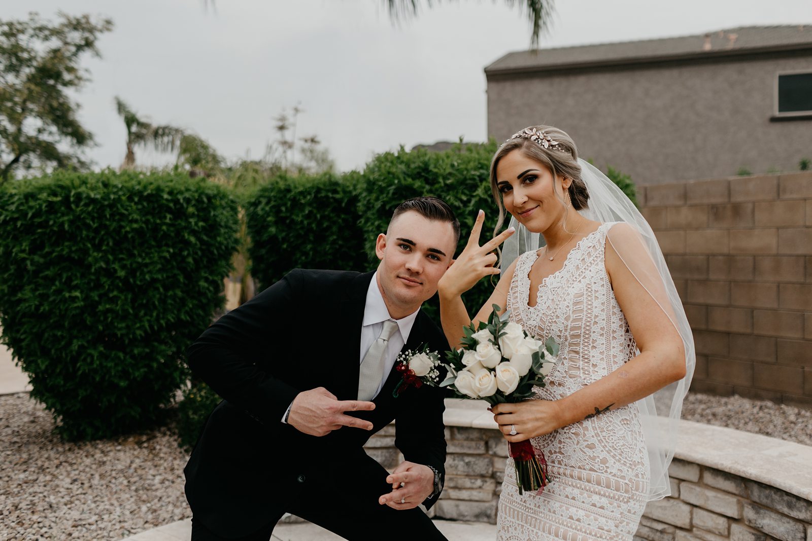 Fighting groom being silly throwing up peace signs for their casual intimate backyard wedding in phoenix Arizona