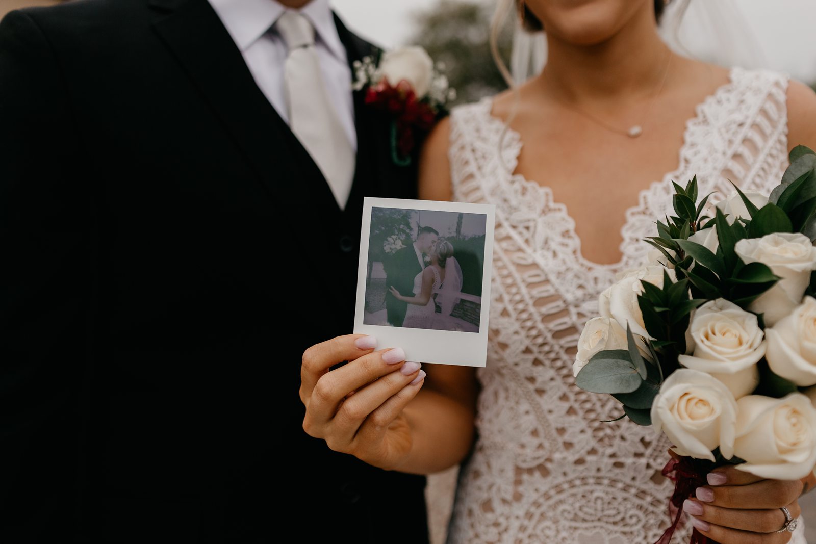 Bride and groom holding polaroid print photo on their wedding day