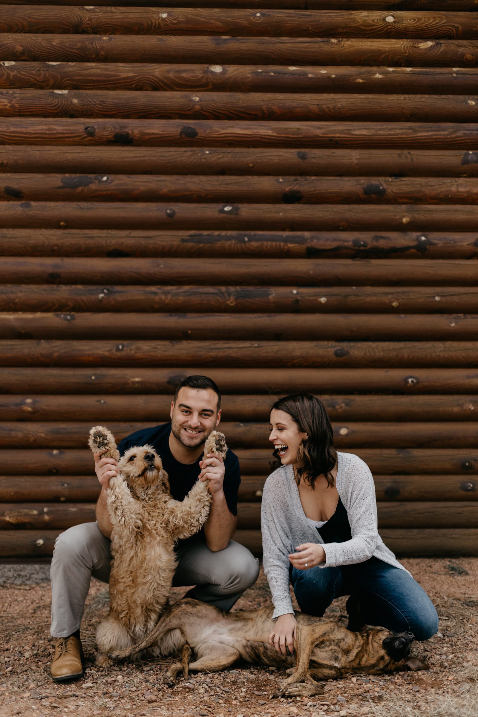 Arizona mountain top engagement couple being silly with their dogs in front of a log cabin