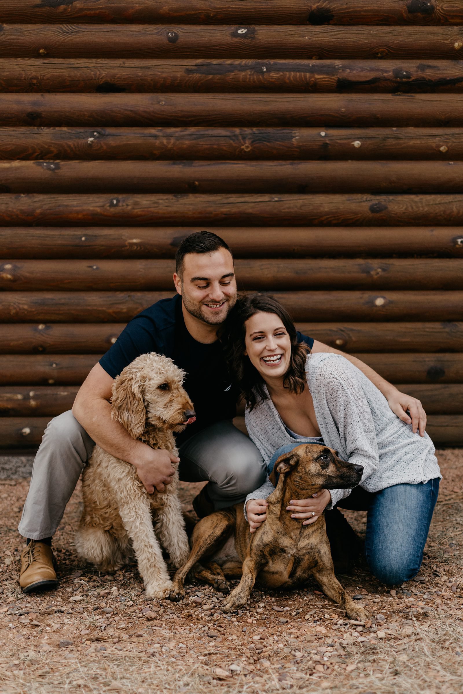 Couple, hugging with their dogs in front of a log cabin in Payson, Arizona