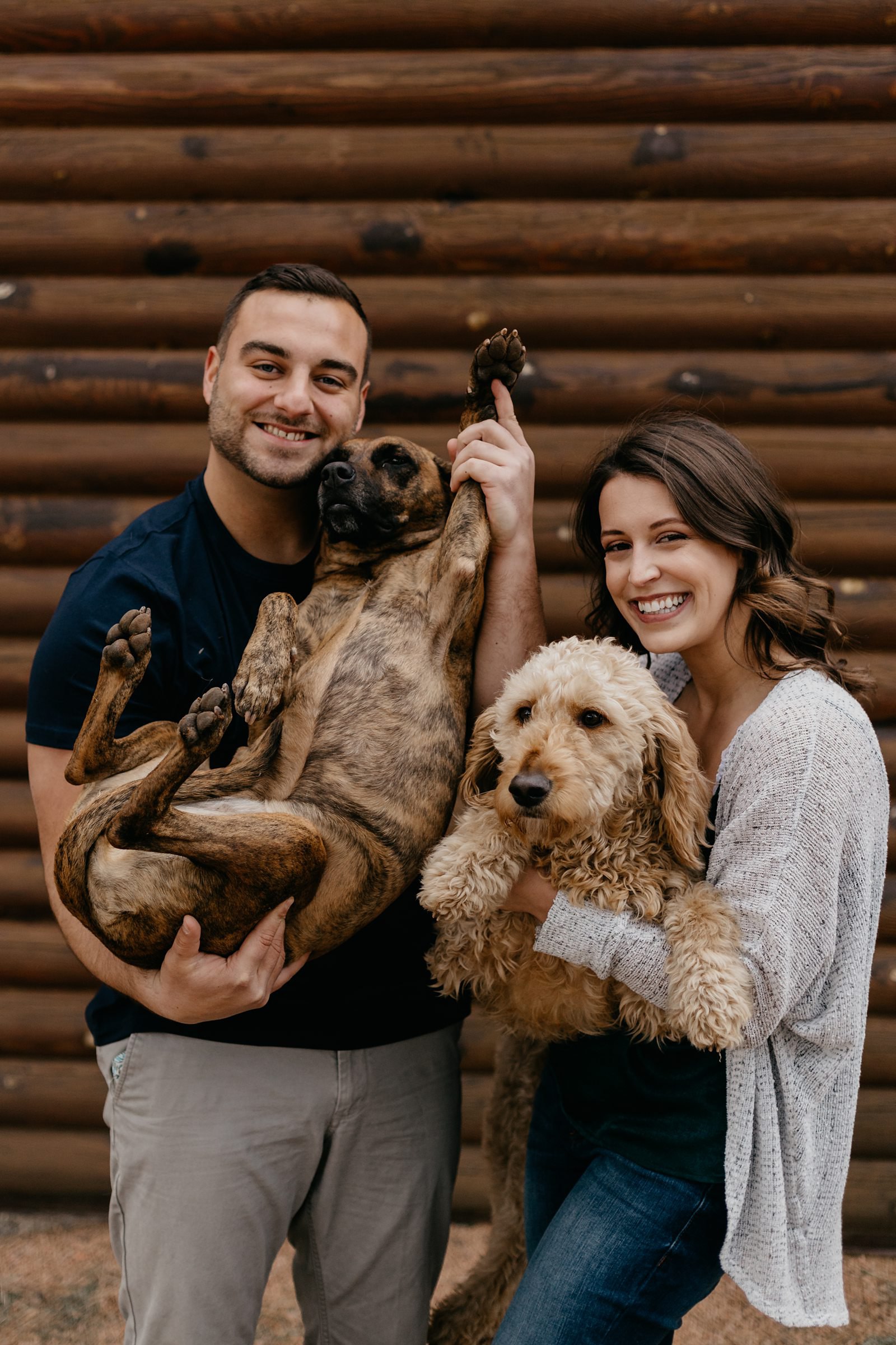 Couple being silly with their dogs in front of a wood cabin in Payson Arizona