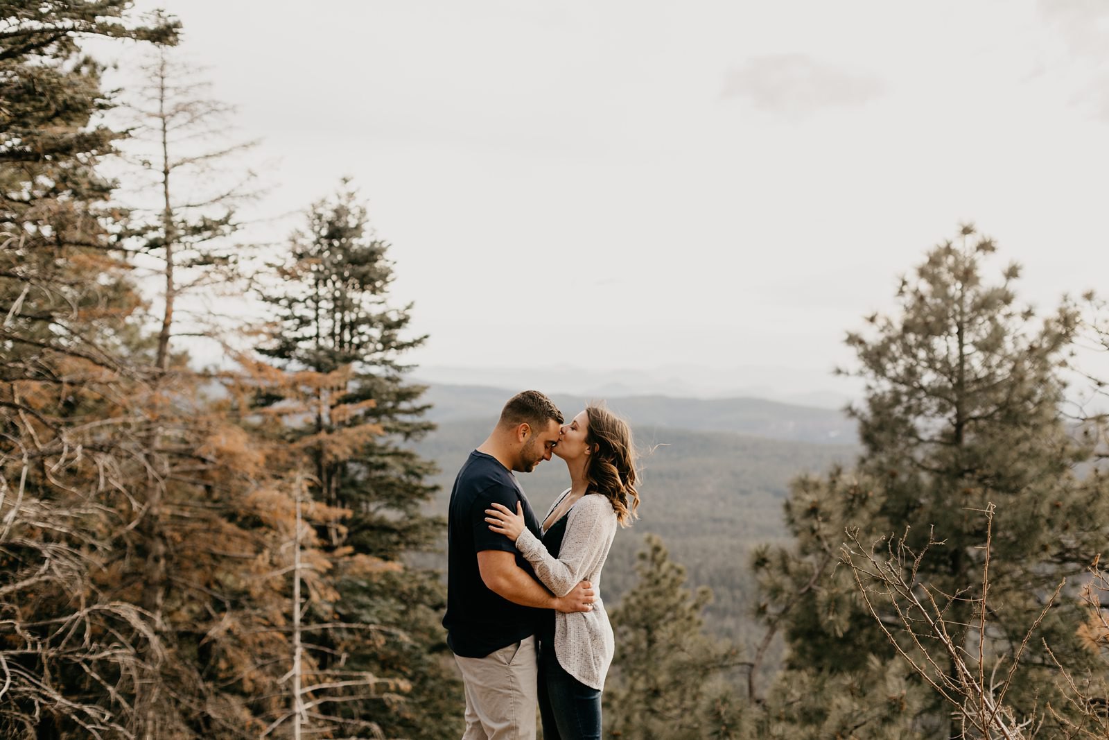 Arizona pine tree engagement pictures couple hugging on mountaintop couple, kissing overlooking the Mogollon rim in Payson