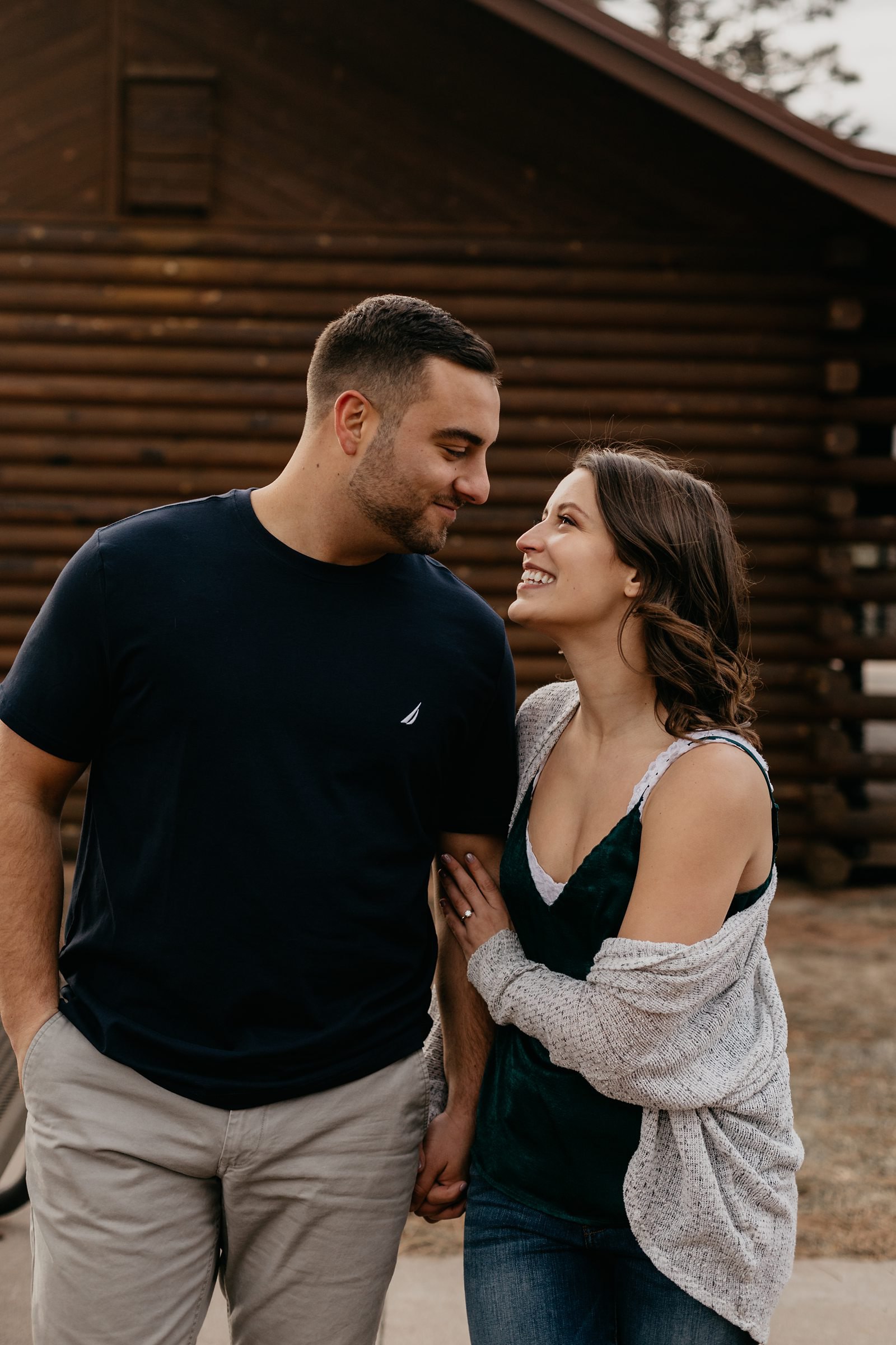 Payson and coupl, laughing together in front of a log cabin