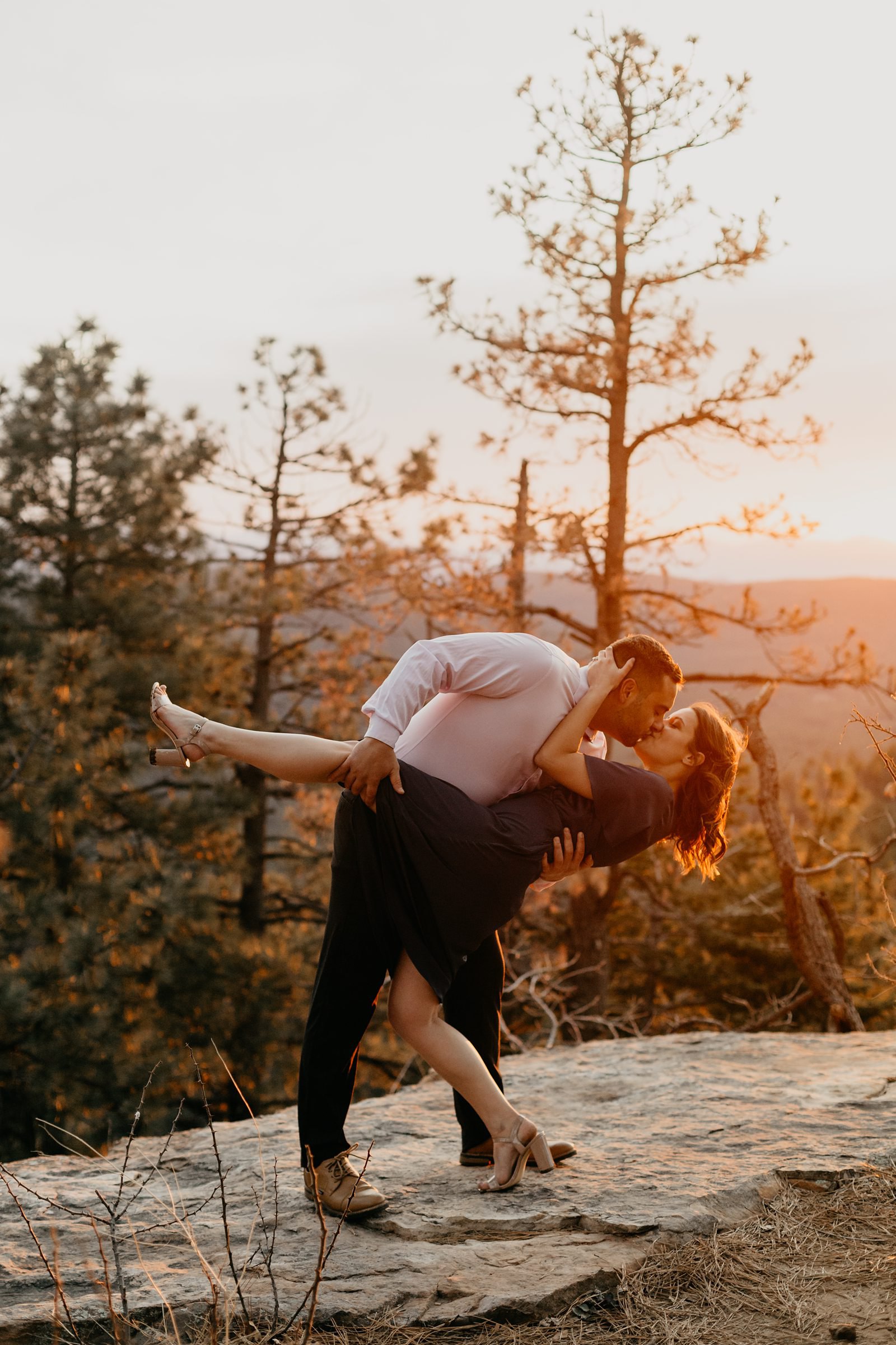 winter Mogollon Rim Engagement dip and kiss on a mountain top with pine trees in Northern Arizona