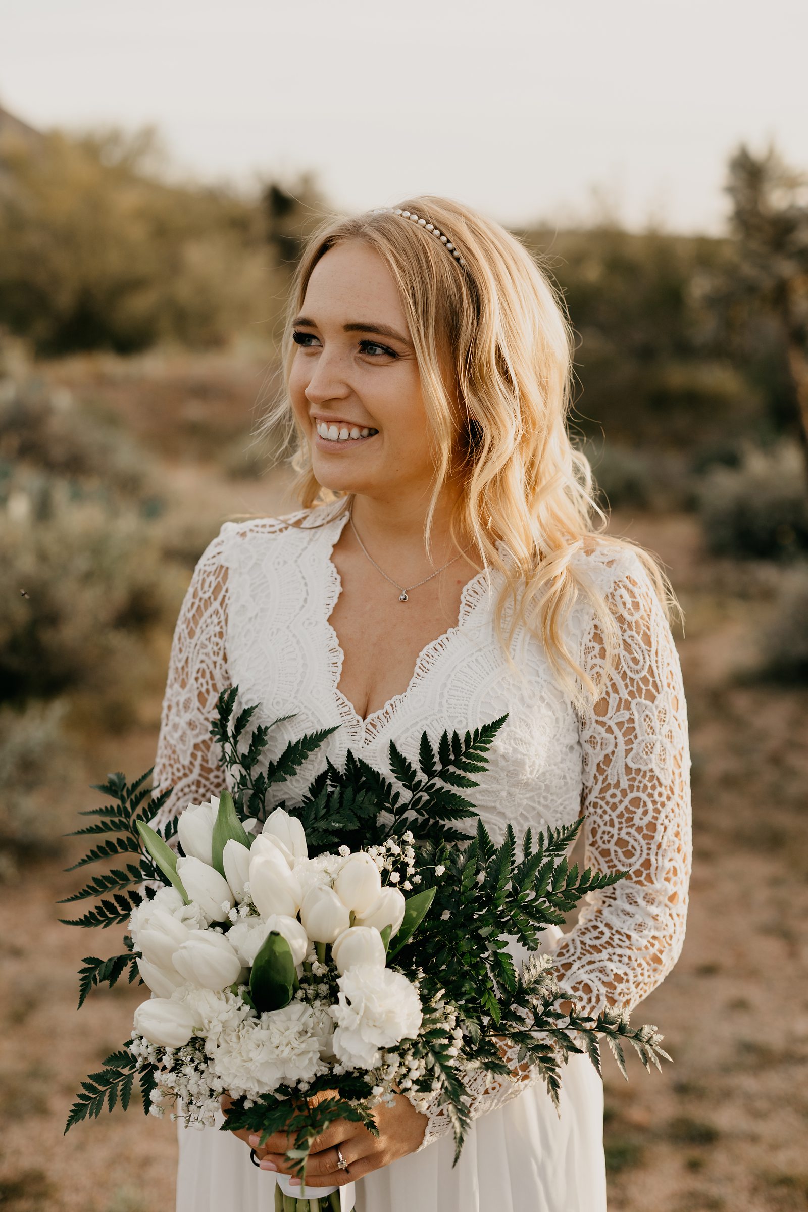 Portrait of bride in the desert of arizona in boho v neck lace dress white tulip bouquet