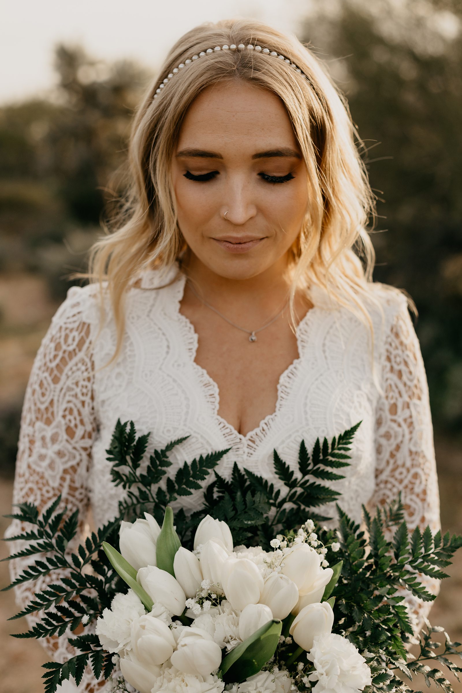 Portrait of bride in the desert of arizona in boho v neck lace dress white tulip bouquet