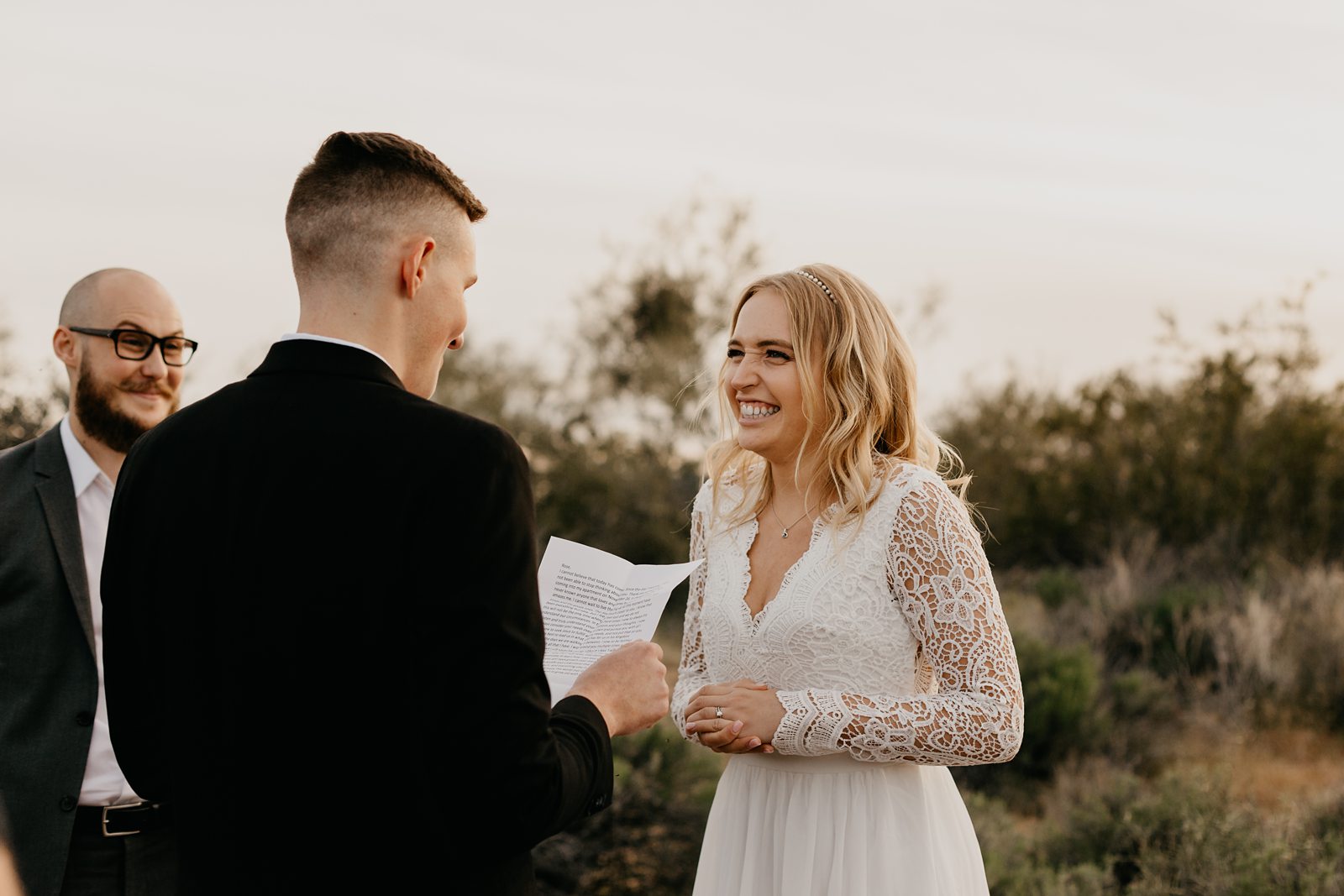 bride smiling beaming with joy with groom exchanging vows in the superstition mountains for their adventurous intimate wedding in the phoenix arizona desert