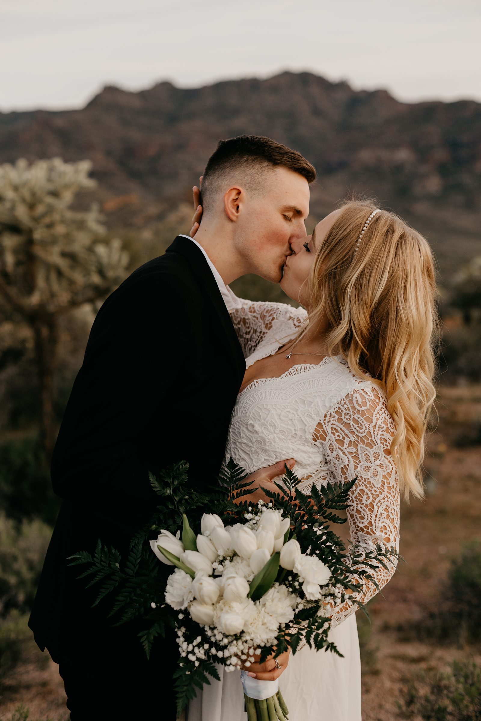 bride and groom kissing at their desert intimate elopement phoenix AZ bride wearing boho lace dress