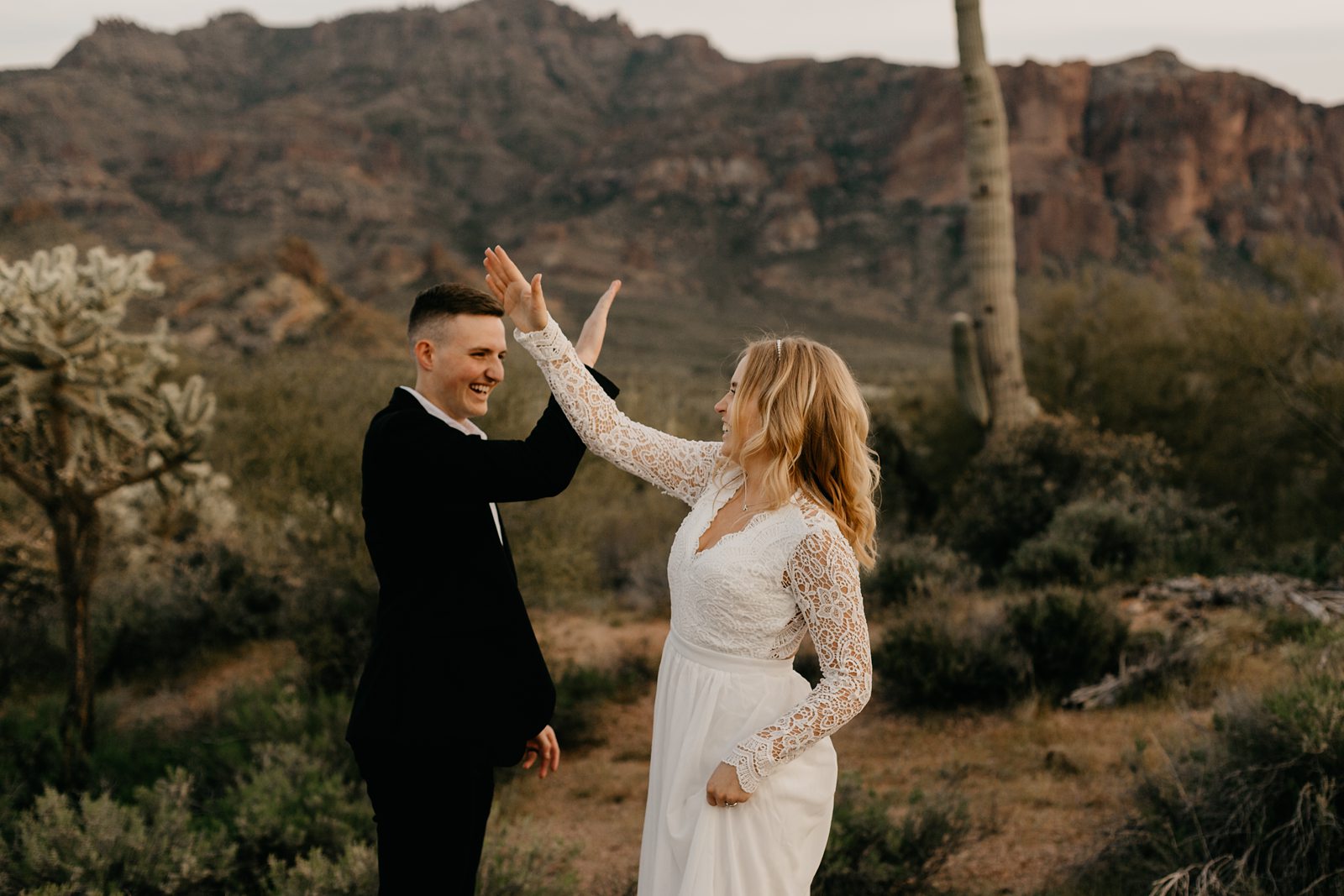 silly fun wedding picture of bride and groom high-fiving in the arizona desert