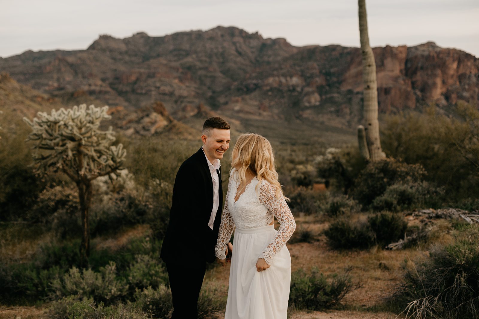 silly fun wedding picture of bride and groom high-fiving in the arizona desert