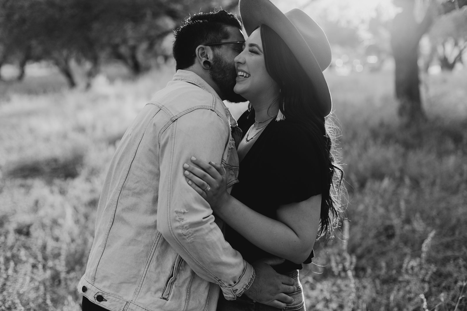 black and white engagement photo of a couple in arizona with grass and trees in the background