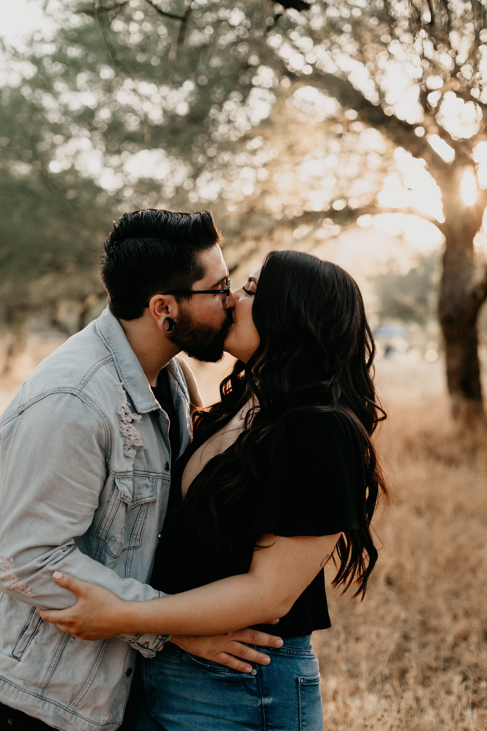 young couple kissing around grass and trees in phoenix arizona