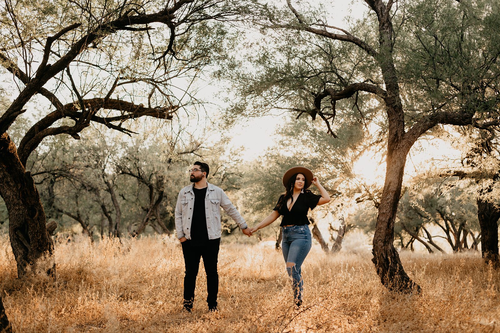 couple holding hands around grass and trees at coon bluff engagement photos in phoenix arizona