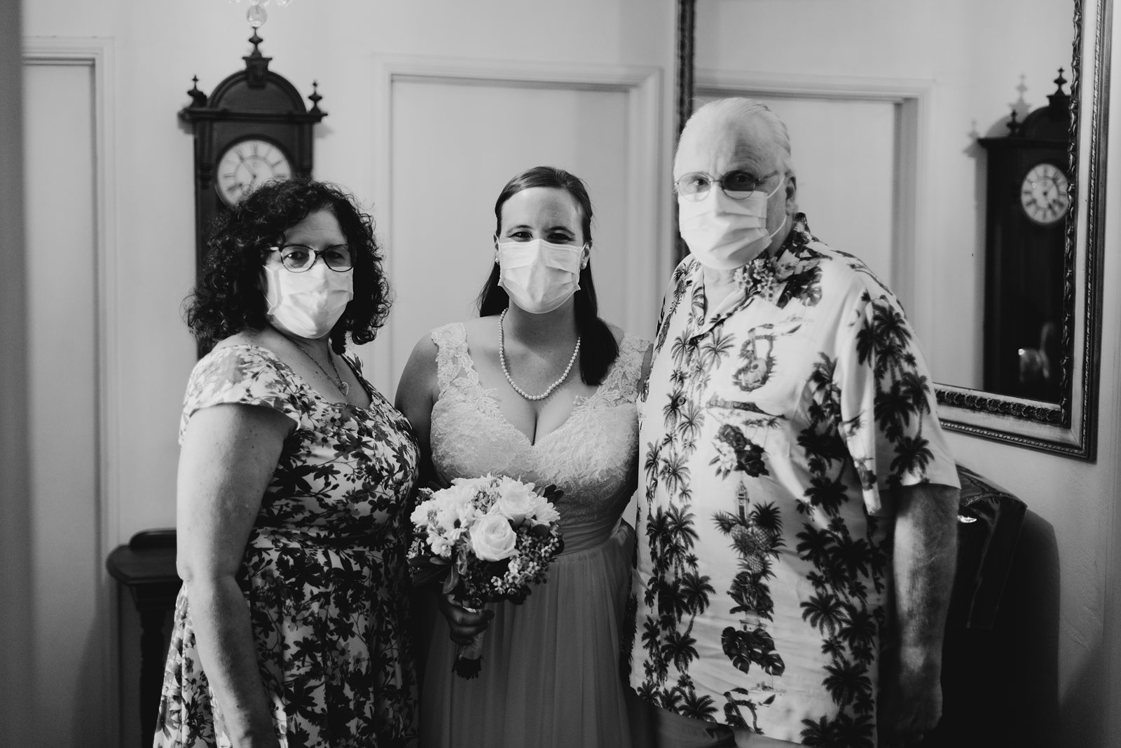 black and white photo of bride and her parents wearing face masks