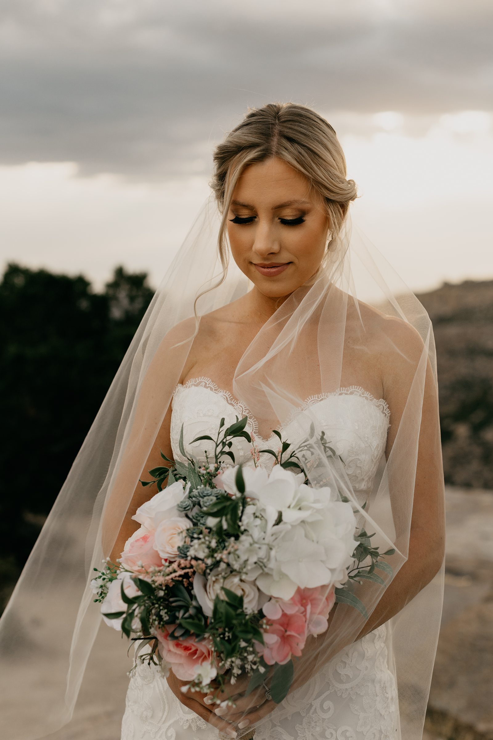 Bride with veil looking down at bouquet