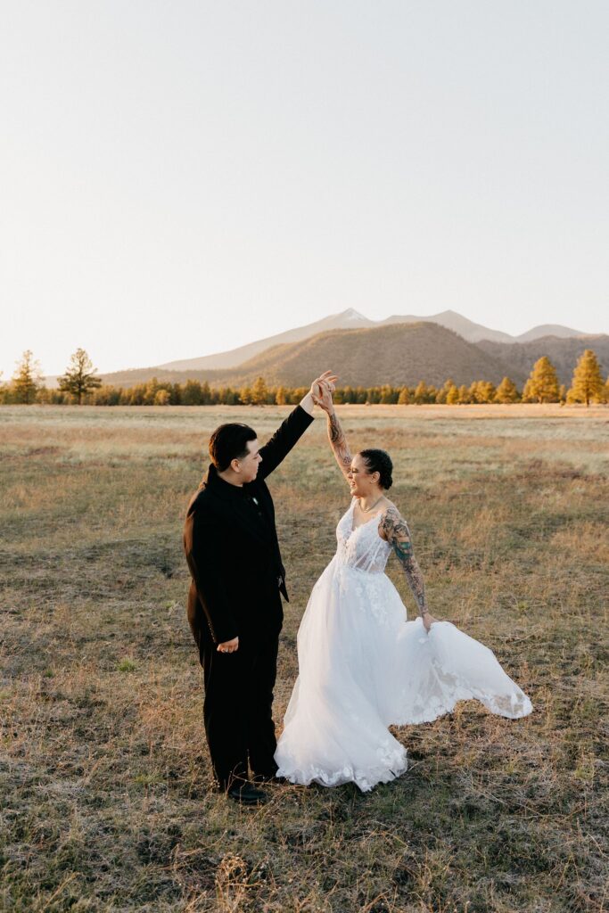LGBTQ Buffalo Park elopement photos, couple twirling in a field with mountains in the back. One of the best Arizona Elopement Locations