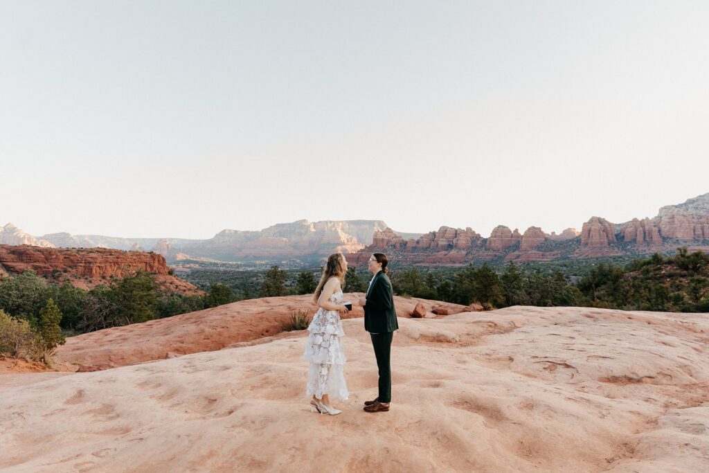 Queer sunrise red rock hiking elopement brides holding hands laughing sedona AZ, one of the best Arizona locations