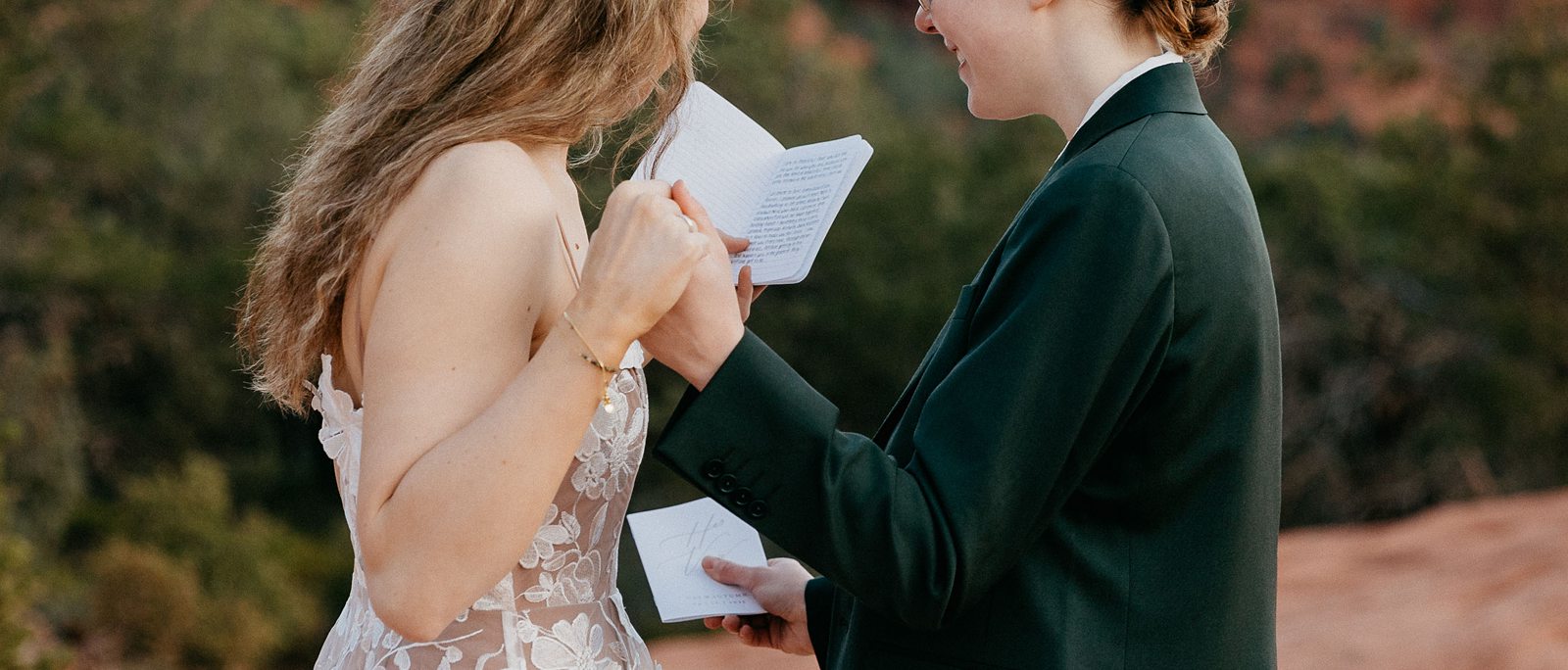 brides holding hands and vow books during elopement ceremony