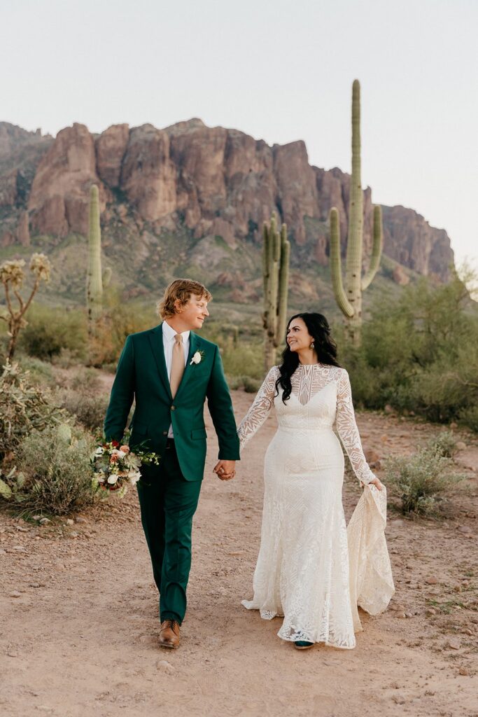 Intimate eloping couple walking hand in hand away from the iconic Superstition Mountains, one of the best Arizona elopement locations