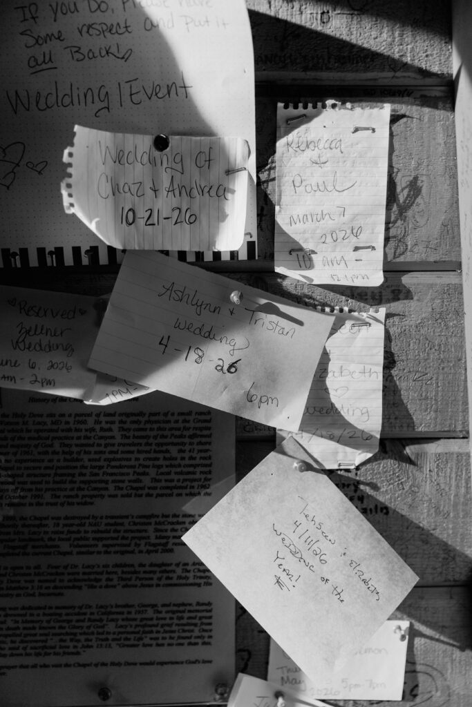 Black and white image of handwritten save-the-date notes, pinned to a cabin wall